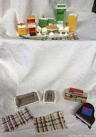 Full view of the colorful Mid-Century Modern miniature dollhouse furniture set including kitchen, dining, bathroom items, and mini electronic devices arranged on a white fabric backdrop.