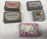 Three Swedish La Petite safety matchboxes with vintage style labels, along with two decorative pillboxes: one with floral tapestry top, the other with micro mosaic on lid.