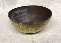 Top angle showing the interior of the brass singing bowl with visible patina and some discoloration.