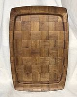 Full view of the rectangular teak tray showing checkered wooden block pattern and shallow lip around edges.