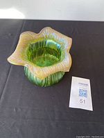 Front and top-left view of green iridescent art glass vase showing ruffled rim