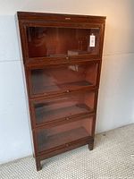 Front view showing all four stacked sections with glass-front doors and brass hardware.