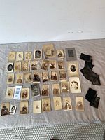 Overview of entire lot showing paper-mounted photos and stack of black tintypes