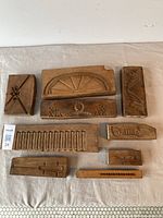 Full group of nine early boxwood molds laid out on cloth surface, visible varied architectural decorative motifs with wooden textures showing signs of wear and age.