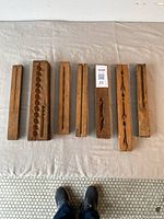 Seven antique boxwood molds laid out on fabric background, showing full length of each and varied carved patterns.