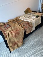 Nine assorted vintage cloth bags and sacks laid out on black tablecloth, showing various colors, logos, and printed text.