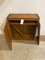 Front view of the antique wooden cupboard with both doors open showing interior shelf and wooden support brace.