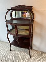 Full front view of the antique mahogany curio cabinet showing bow front glass doors, carved top, and cabriole legs.