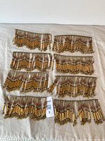 Eight pieces of vintage amber glass bead fringe arranged on fabric background, showing full lot and size scale.