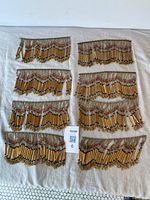 Photo showing all 8 pieces of amber vintage glass bead trims laid out on a white cloth, displaying their size and quantity.