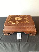 Front view of the antique Canadian walnut needlepoint footstool showing the floral needlepoint cushion and bracket feet design.