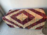 Full view of quilt draped over bench showing overall log cabin pattern and color distribution