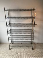 Front view of six-tier metal wire shelving unit on wheels, showing overall structure and clean condition.