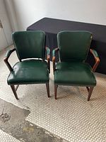 Two matching chairs side by side on tiled floor with black backdrop