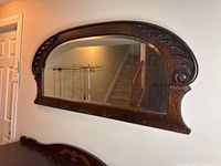 Full front view of antique mirror showing carved wooden frame and beveled glass.
