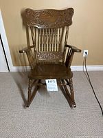 Front view of wooden antique rocking chair showing press back design, carved details, and turned wood elements
