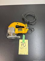 Top view of yellow and black Dewalt electric jig saw showing power cord, handle, and base plate, with a handwritten tag showing lot number 70