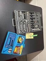 Overview of multi-tool kit and staple tool kit with cases on black surface.