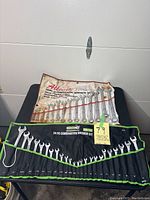 Photo showing 14-piece white/red plastic roll and 24-piece black fabric roll with combination wrenches inside.