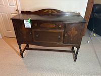 Front view of antique wooden buffet showing decorative carved accents and doors closed