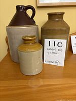 Photo showing all three ceramic vessels together: large jug with dark brown top and handle, large and small crocks with beige and brown glaze.