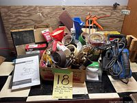 Wide view of the lot showing the assorted sanding belts, tapes, goop, brushes, and other workshop items arranged in a box with the belt sander instruction manual beside it.