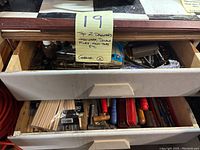 Two wooden drawers partially open showing assorted dowels, files, and various hardware items inside.