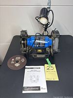 Full view of Mastercraft 8 inch bench grinder with flexible work lamp, showing two grinding wheels, electrical cord, grinding disc, and instruction manual.