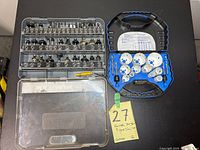 Maximum router bit set and Mastercraft hole saw cutting tips displayed in their cases on a black surface with a yellow lot tag.