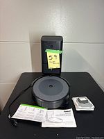 Vacuum, Clean Base station, extra filter with bag, instruction manuals arranged on black tabletop