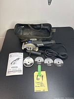 Dremel Ultra Saw electric saw Model US40 with side handle, cord, carrying case, manual, and saw blades laid out on table.