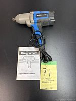 Mastercraft impact wrench with attached power cord and instruction manual on black surface.
