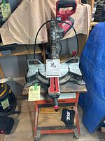 Front view of the SKIL sliding miter saw mounted on the orange Hirish work station showing saw with manual on base.