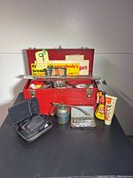 Full view of lot with red metal toolbox, tubes, oil can, socket set, and Foxwell code reader case