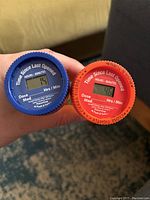 Top view of 2 TimerCaps digital medicine bottle caps, one blue, one red showing the Time Since Last Opened display screen and dose instructions.