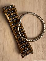Two marigold-colored stretch bracelets with rhinestones, one thick and one thin, display of details