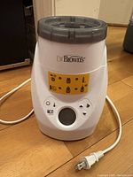 Close-up front view of Dr. Brown's bottle warmer showing control buttons, LCD screen and yellow instruction label.