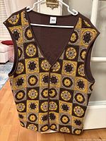 Front view of the ZARA vest showing the crochet pattern with mustard, brown, and beige colors and button down closure.