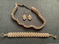 Full bridal set photo showing necklace, bracelet, and earrings arranged on a grey surface.