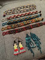 View of entire jewelry lot arranged on gray fabric surface. Shows all bracelets, choker necklace, and two pairs of earrings.