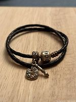 Black leather double-wrap Pandora bracelet with a silver-tone charm featuring a painter's palette with colorful stones and a paintbrush attached