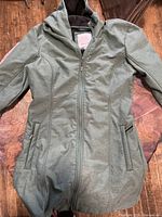 Front view of the green Bench women's spring jacket laid flat on a wooden floor.