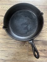 Top view of the black cast iron frying pan showing the cooking surface and pouring spouts.