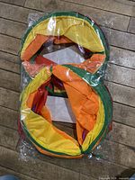 Two rainbow colored cat tunnels packed in plastic on floor, showing bright yellow, orange, green, purple fabric sections.