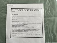 Top-down shot of gift certificate printed on white paper with event and contact fields