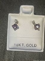 Front view of earrings showing square amethyst and small round diamond set in 10K gold with backing card labeled 10KT. GOLD.