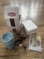 Photo showing the blue hobnail ceramic fragrance warmer, power cord, original packaging, and sealed additional accessories.
