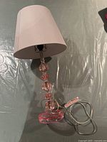 Full view of the pink crystal table lamp on a flat surface showing the lamp shade, base, and cord.