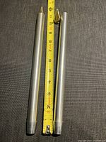 Two aluminium taper candle molds side by side with measuring tape showing length approximately 12 inches