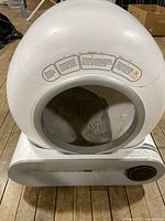 Full view of Robo Kitty Litter automatic cat litter box showing white spherical hood with entrance opening and base unit with control dial.